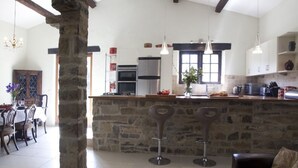 Una cocina amplia con una isla de piedra, electrodomésticos modernos y un comedor con candelabro.