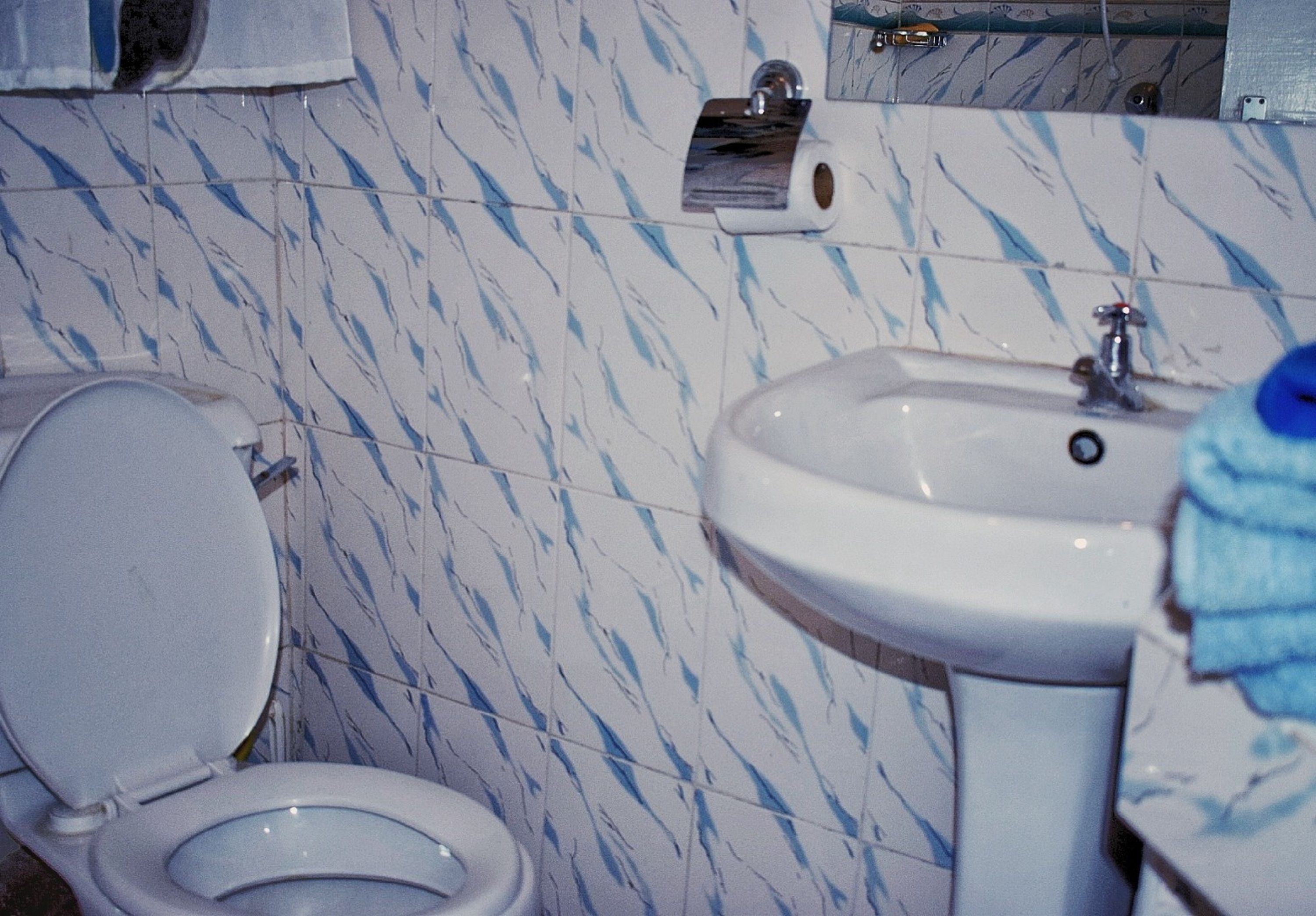 A bathroom with a toilet, sink, and marble-patterned walls.