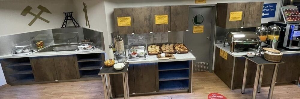 A breakfast bar with a variety of food items, a coffee machine, and a juice dispenser.