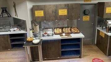 A breakfast bar with a variety of food items, a coffee machine, and a juice dispenser.