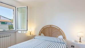 A bedroom with a bed, a window, and two bedside tables with lamps. - Michelangelo I by Interhome (Marina Pietrasanta)