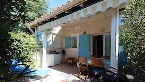 Une terrasse avec un barbecue, une table et des chaises.