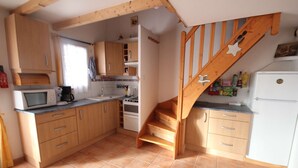 Une cuisine avec des meubles en bois, un four à micro-ondes, une cuisinière et un escalier en bois.