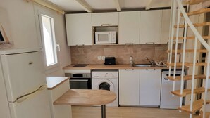 A compact kitchen with a washing machine, microwave, and a small wooden table. - Corner villa located in a secured residence with pool, for 4 people, at only 400m from the beach... (PORTIRAGNES)