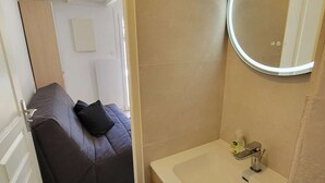 A compact bathroom with a round mirror, a sink, and a small storage cabinet. - Corner villa located in a secured residence with pool, for 4 people, at only 400m from the beach... (PORTIRAGNES)