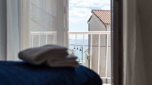 A room with a bed and a view of the sea through a balcony railing. - Apartman Tonci (Primosten)