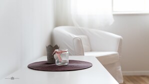A white table with a woven placemat, a glass jar with a pink ribbon, and a decorative item resembling a crown. - Apartman Tonci (Primosten)