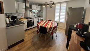 Una cocina compacta con una isla central, una mesa de comedor con sillas y un refrigerador.