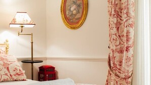 Et hotelværelse med en seng, en telefonkiosk, en lampe og et billede på væggen.