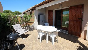 Un patio con mesa y sillas, una parrilla y una puerta con cerramiento de madera.