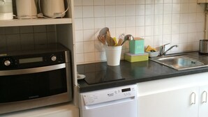 A kitchen with a dishwasher, oven, and a coffee maker on the counter. - Apartment-cottage of the church (Châteauneuf-sur-Loire)