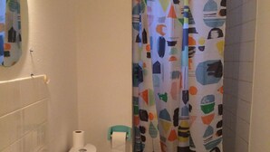 A bathroom with a white sink, toilet, and shower curtain with abstract patterns. - Apartment-cottage of the church (Châteauneuf-sur-Loire)