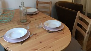 A dining table with plates, cutlery, a glass, and a bottle. There are chairs around the table, and a lamp is on the wall. - Apartment-cottage of the church (Châteauneuf-sur-Loire)
