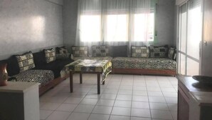 Uma sala de estar com sofá, mesa de centro e janela com cortinas.