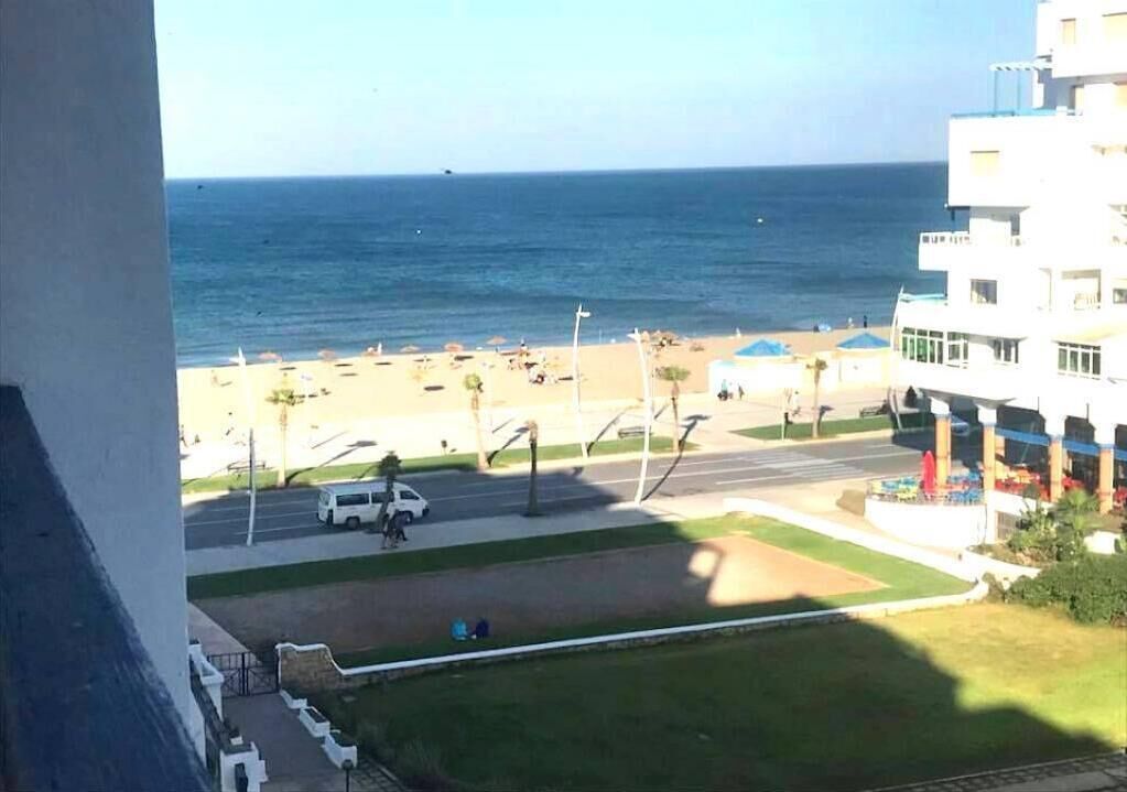Une vue d’une plage avec une route et des bâtiments au premier plan.