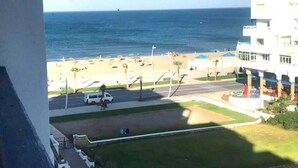 Vista de uma praia, com uma estrada e edifícios ao primeiro plano.