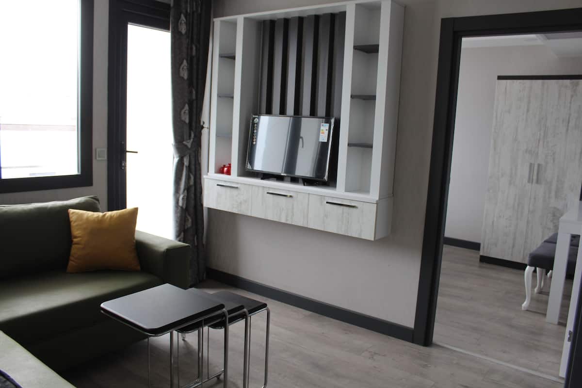 Ein modernes Wohnzimmer mit einer Couch, einem kleinen Tisch und einer integrierten TV-Vitrine.