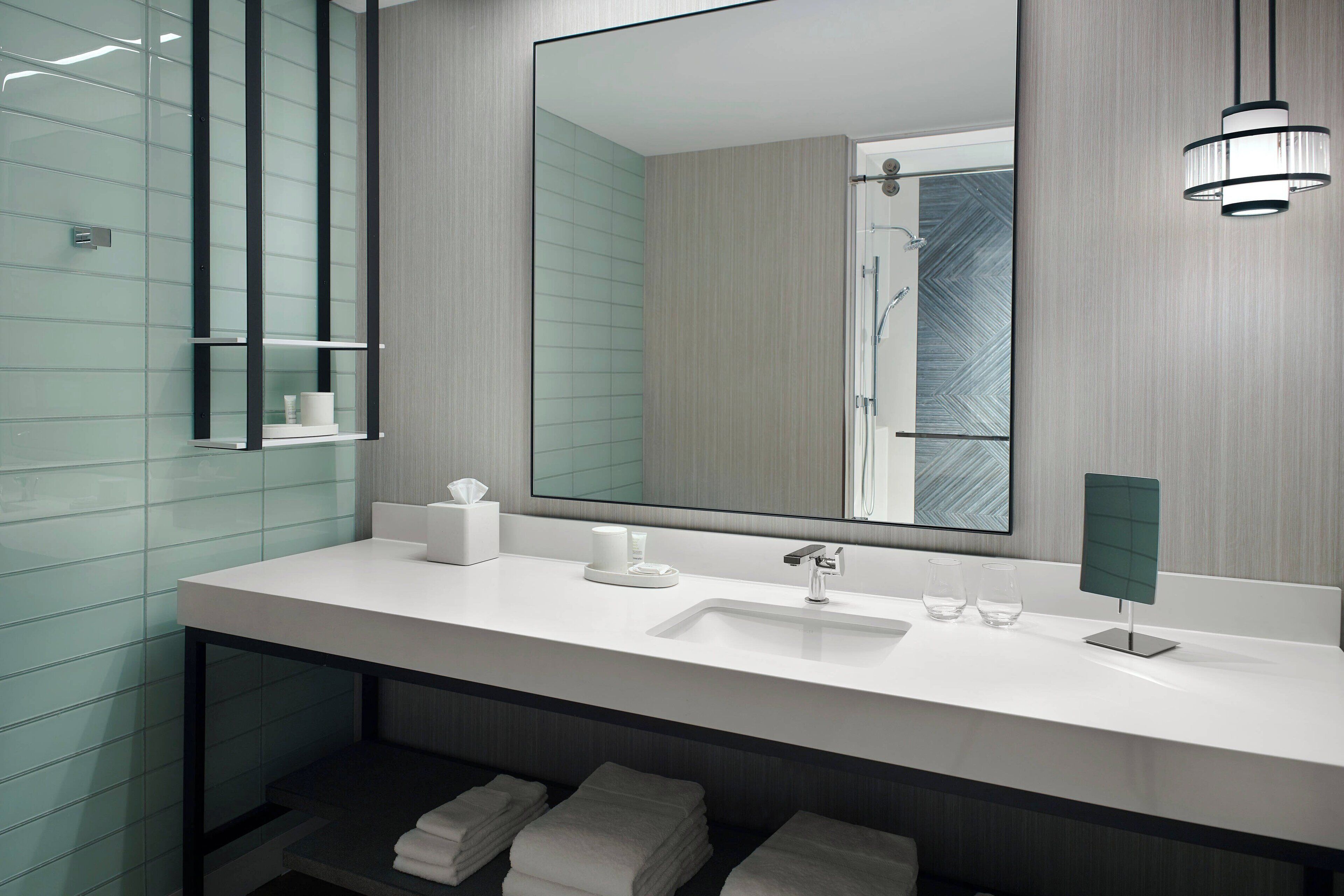 Une salle de bain moderne avec un lavabo blanc, un grand miroir et un porte-serviettes.