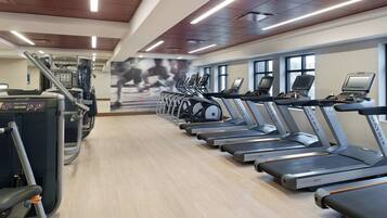 Un gimnasio con cintas de correr, máquina de press de banca y máquina de remo.