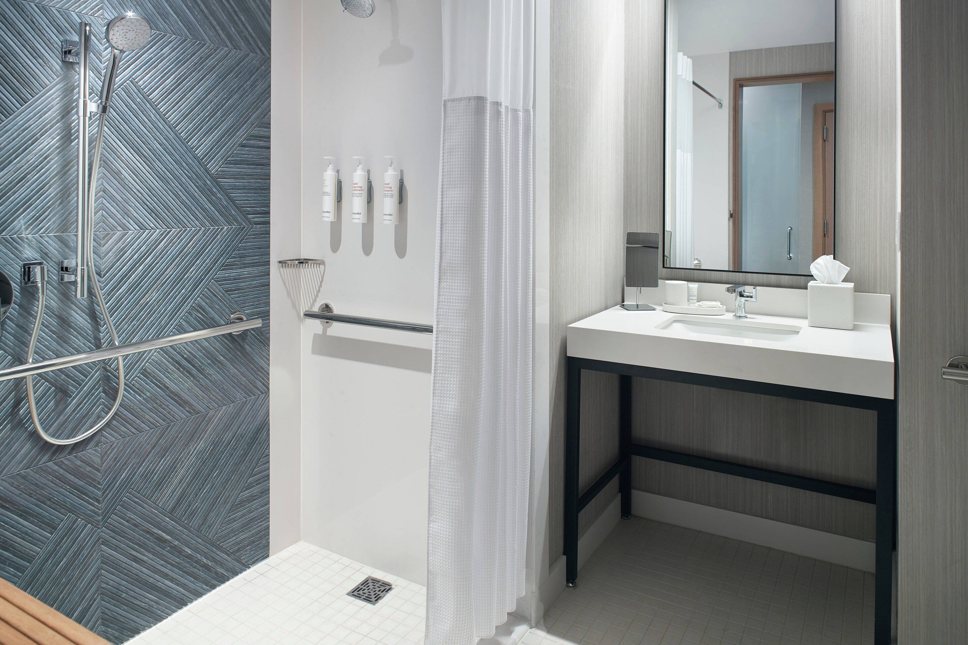 Une salle de bain moderne avec une douche, un lavabo et un miroir.