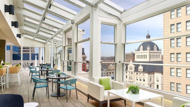 Un espacio interior moderno con techos altos y amplias ventanas que ofrecen vistas a edificios históricos.