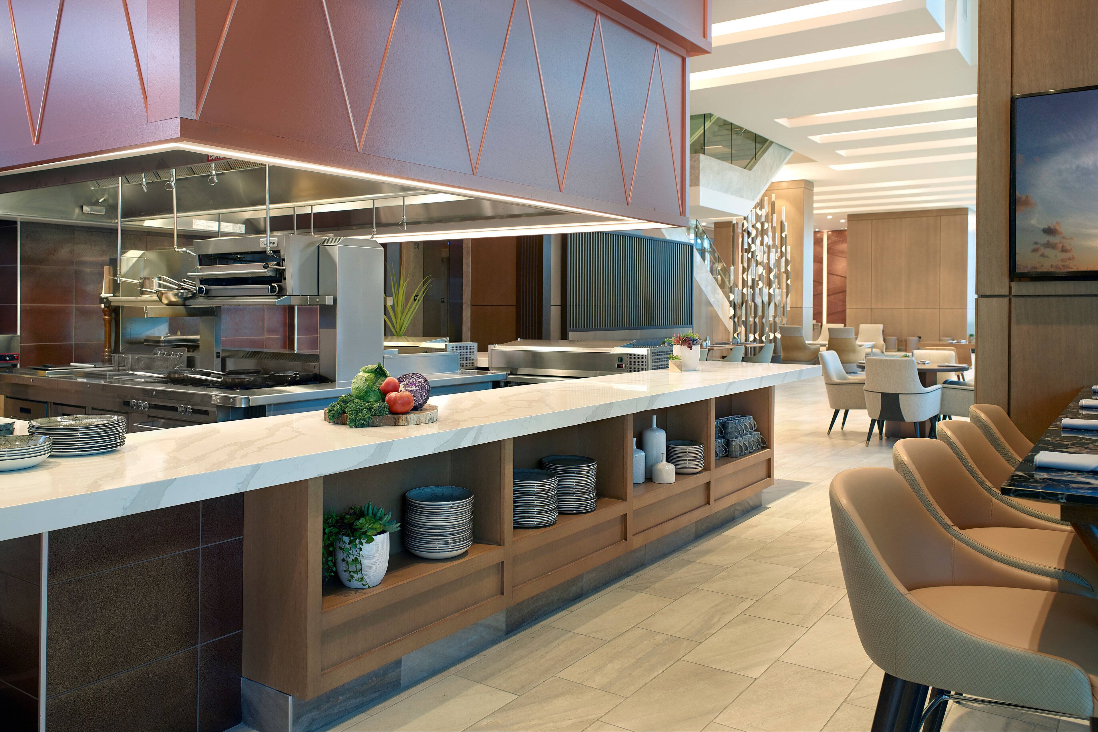 A modern kitchen with a long counter, built-in appliances, and a seating area with chairs and a table.