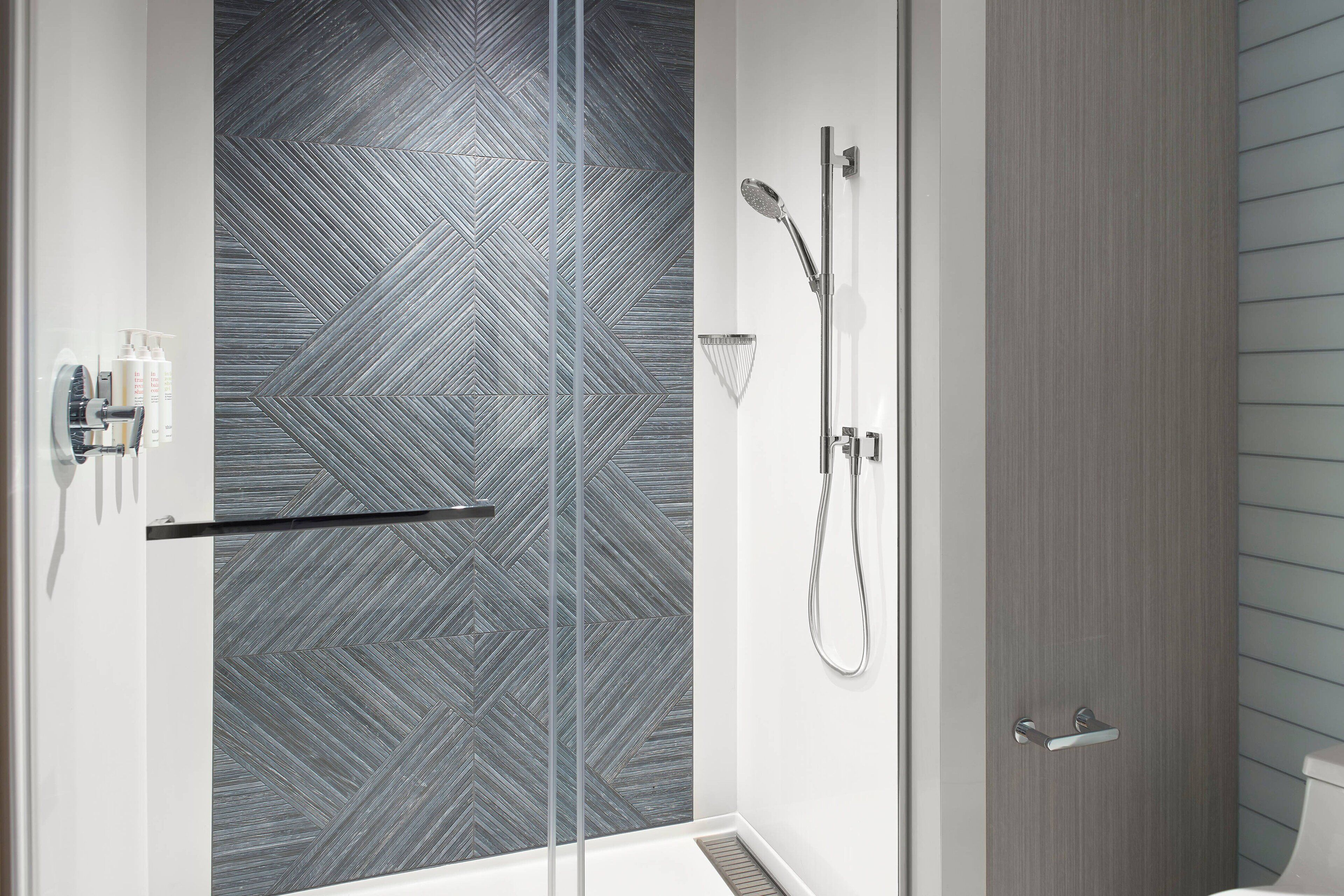 A modern bathroom with a shower, a toilet, and a glass door.