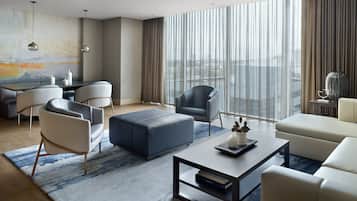 Habitación de hotel moderna con un ventanal grande, un comedor y una zona de estar con una mesa de centro.