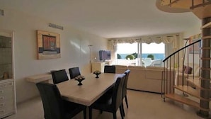 Un espace repas comprenant une table et des chaises, un escalier et une vue sur l’extérieur.