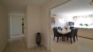 Un coin repas avec une table et des chaises, un vase, et une cuisine en arrière-plan.