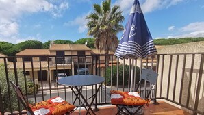 A terrace with two foldable chairs and a table, a blue umbrella, and a view of a building with a tiled roof. - Villa located in Tamaris, 3 bedrooms, half Airco, Wifi, for 7 people, only at 400m from the beach... (PORTIRAGNES)