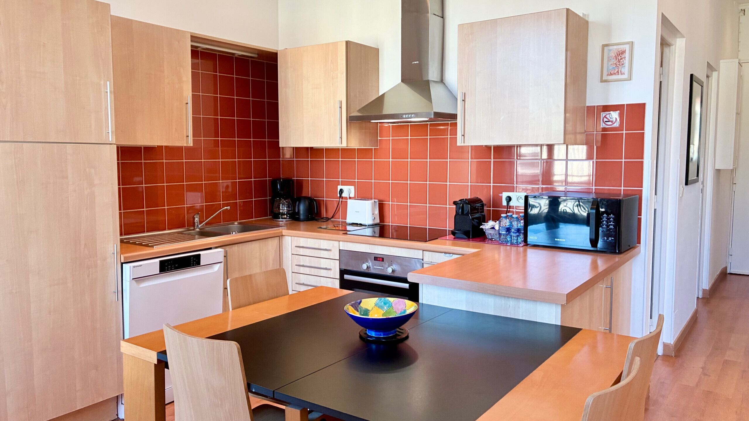 A compact kitchen with wooden cabinets, a black countertop, and a microwave.