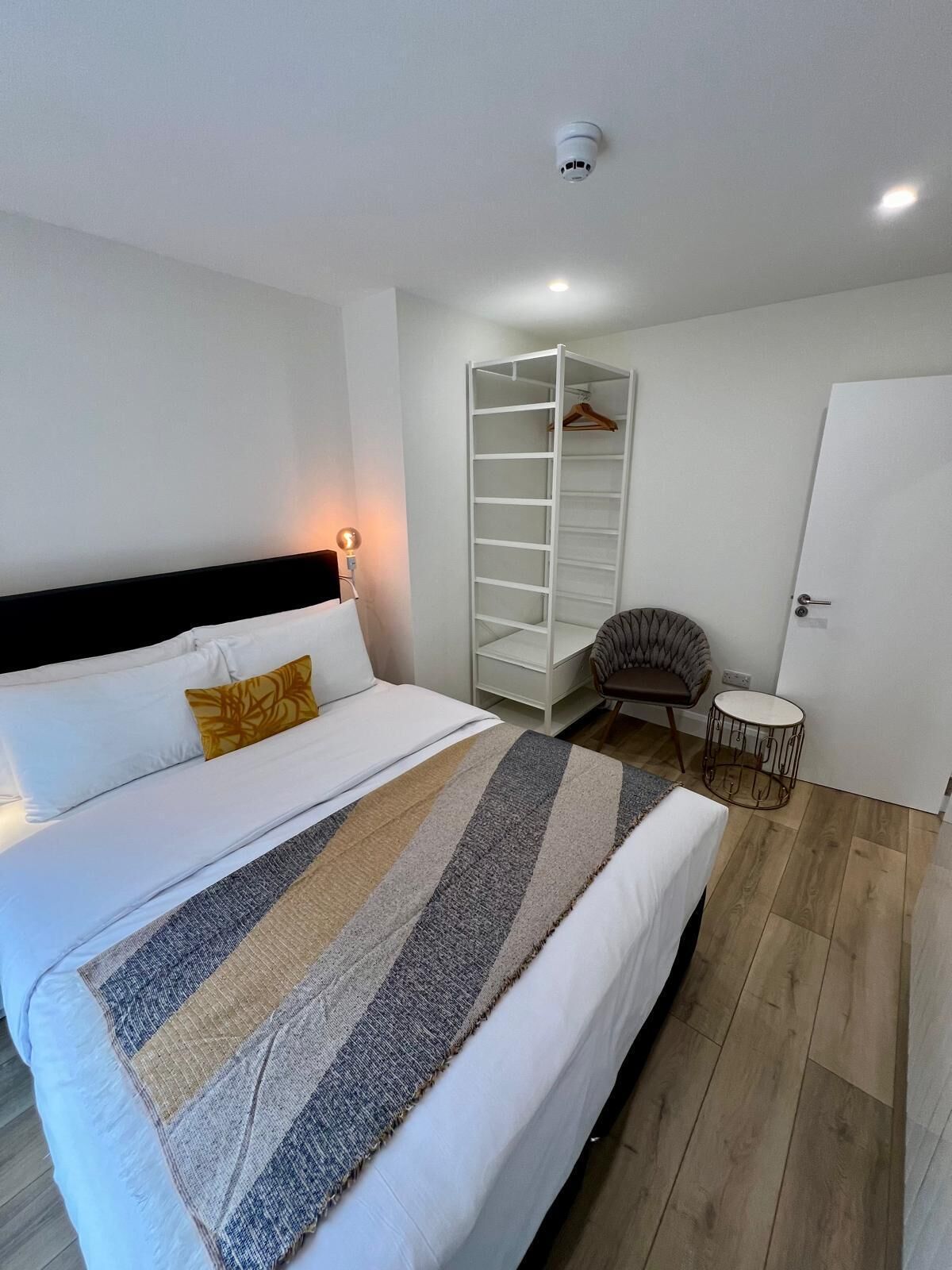 A neatly arranged bedroom with a bed, a wardrobe, a chair, and a small table.