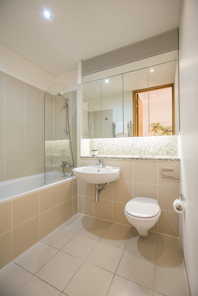 A bathroom with a bathtub, a sink, a toilet, and a mirror.