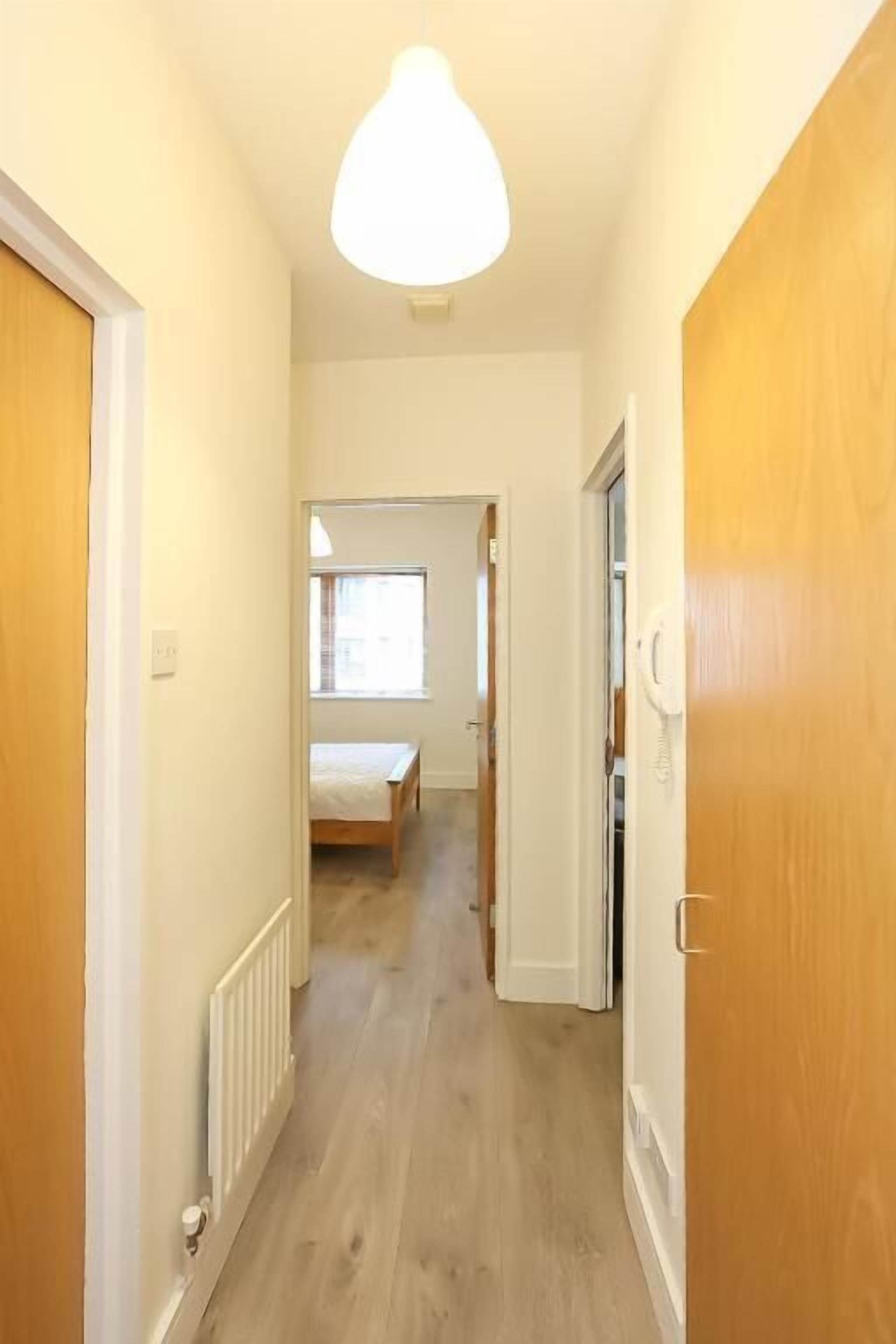 A narrow hallway with wooden doors and a radiator on the left.