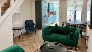 A modern living room with green sofas, a coffee table, and a staircase. - IFSC Townhouse Apartments (Dublin)