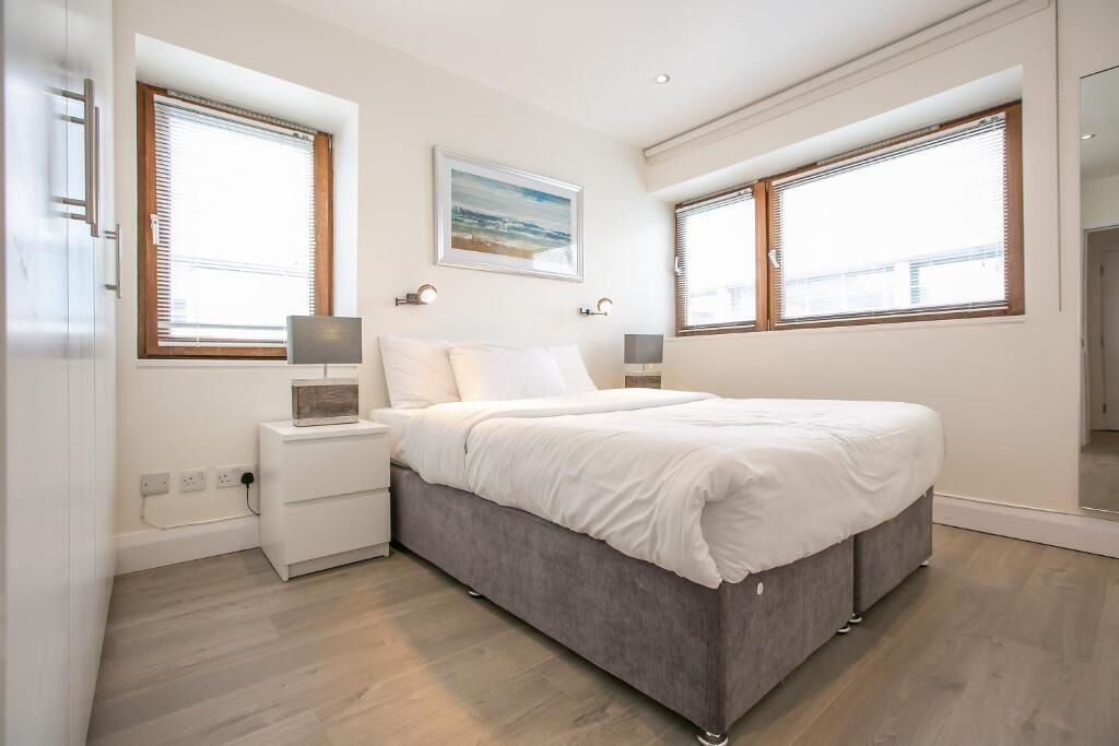 A modern bedroom with a large bed, bedside tables, a nightstand, and a painting on the wall.