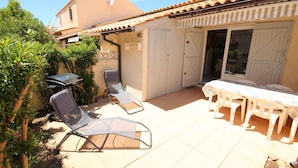 An outdoor patio with a table and chairs, a covered seating area, and a door leading to a covered space. - Nice renovated Holiday house for 5 people, in a secured residence with pool (mid june/mid sept),... (PORTIRAGNES)