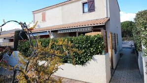 Una casa a due piani con tetto in tegole, una piccola finestra con persiane e un vialetto lastricato.