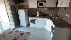 Una cuina compacta amb armaris blancs, microones, cafetera i rentadora.