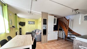 Una cocina compacta con comedor, sofá y escalera.