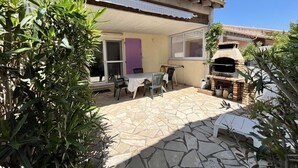Un patio con piso de piedra, mobiliario exterior, un horno de ladrillo y plantas en macetas.