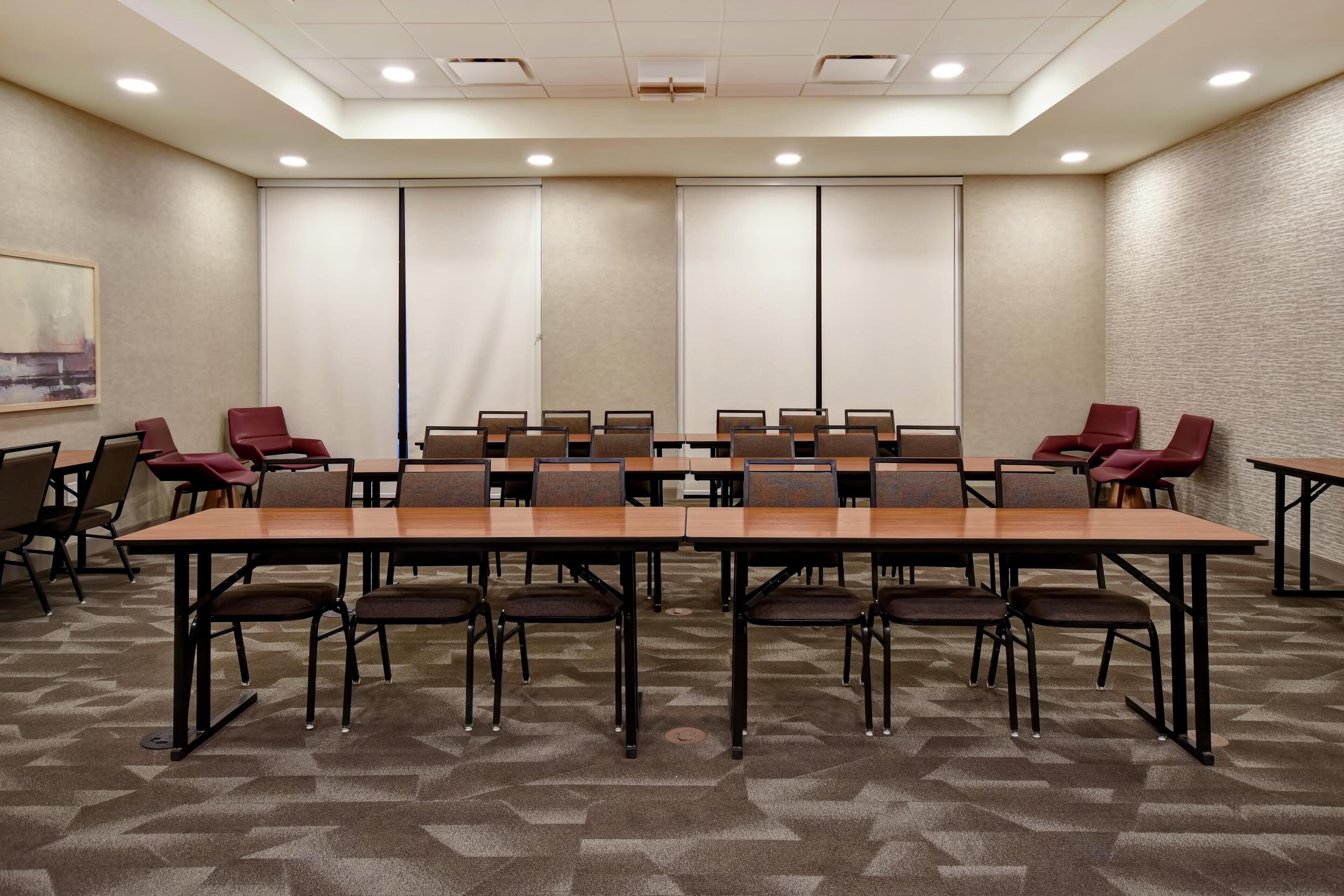 A conference room with a long table, multiple chairs, and a carpeted floor.