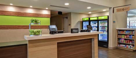 Et hotelreceptionsområde med en trædisk, en grøn væg, et minibar og en selvbetjeningsvandautomat.