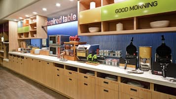 A breakfast bar with a variety of food items and utensils, labeled sections for plates and utensils, and a 'Good Morning' sign.