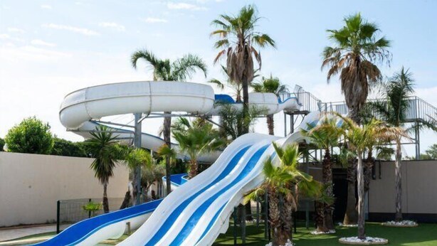 Ein Wasserpark mit mehreren Rutschen und Palmen.
