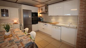 Eine moderne Küche mit weißen Schränken, einem Edelstahlkühlschrank, einem eingebauten Backofen und einem Geschirrspüler.