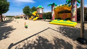 Ein Spielplatz im Freien mit Rutschen, einer Kletterkonstruktion und einem Sandbereich.
