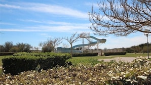 A park with a modern sculpture, neatly trimmed bushes, and a clear sky.