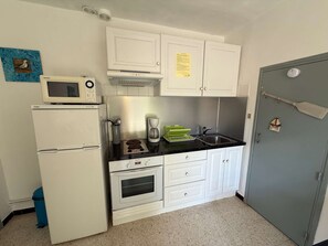 Een koelkast, een microgolfoven, een oven, kookgerei, borden en bestek